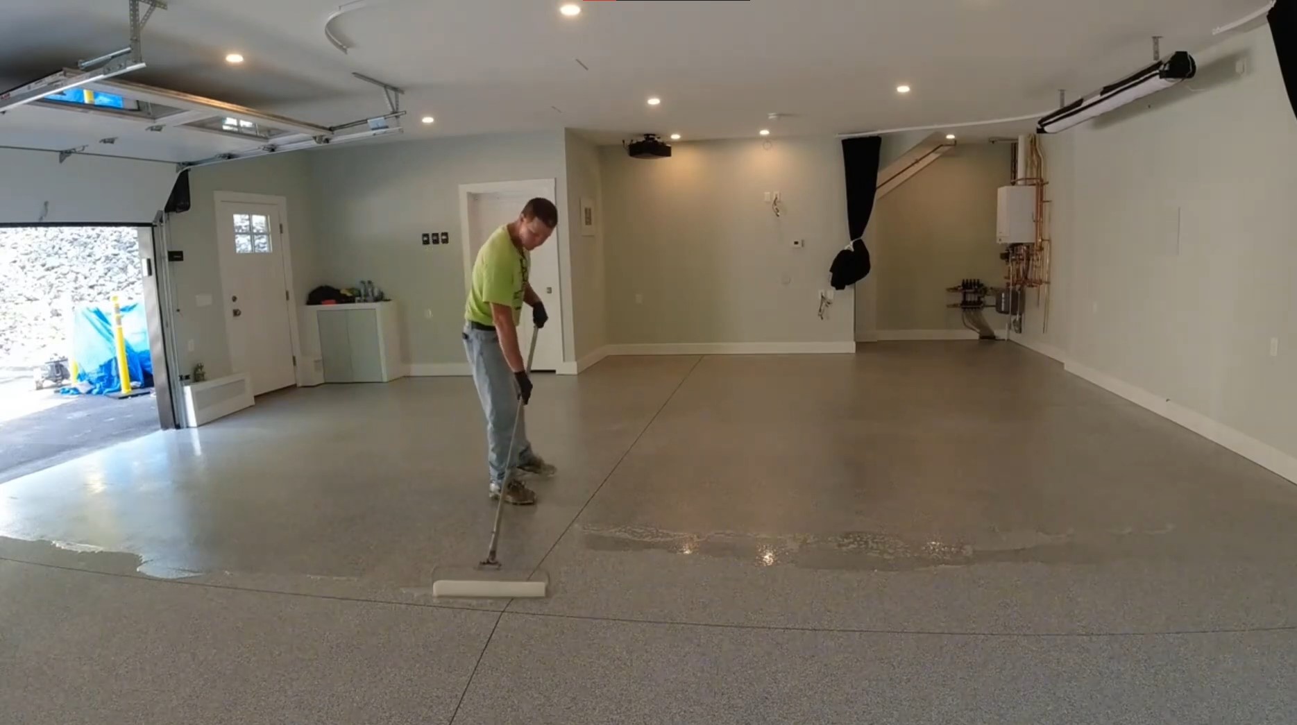 man rolling out epoxy sealant on garage floor