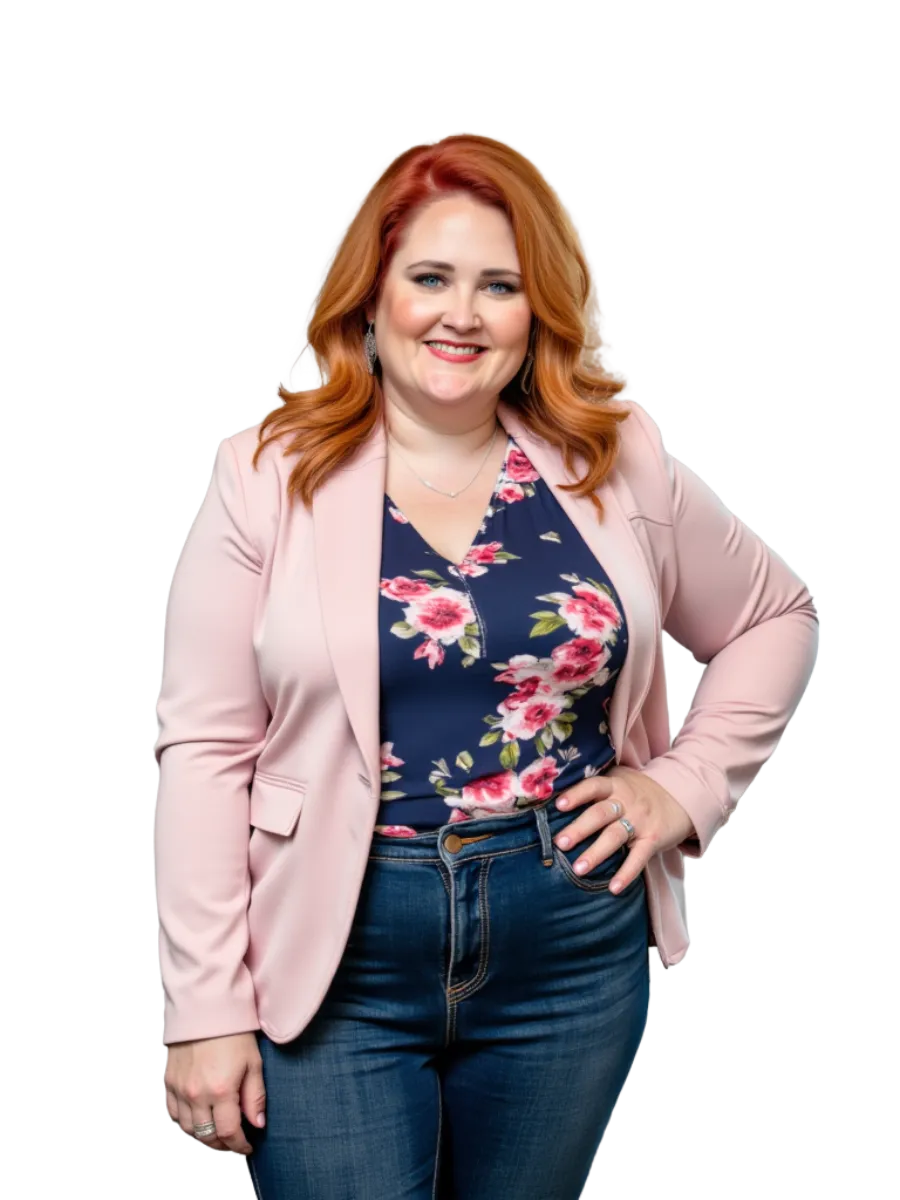 Caitlin, a red-haired professional, is seated confidently in a light beige chair. She’s wearing a denim jacket over a floral top, paired with jeans. Caitlin smiles warmly, radiating approachability and professionalism, ready to connect and strategize.