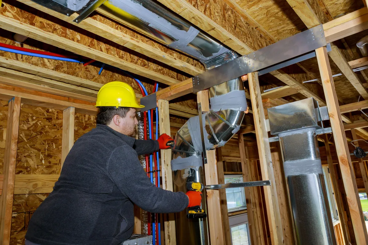 HVAC worker making adjustment to airs system in attic