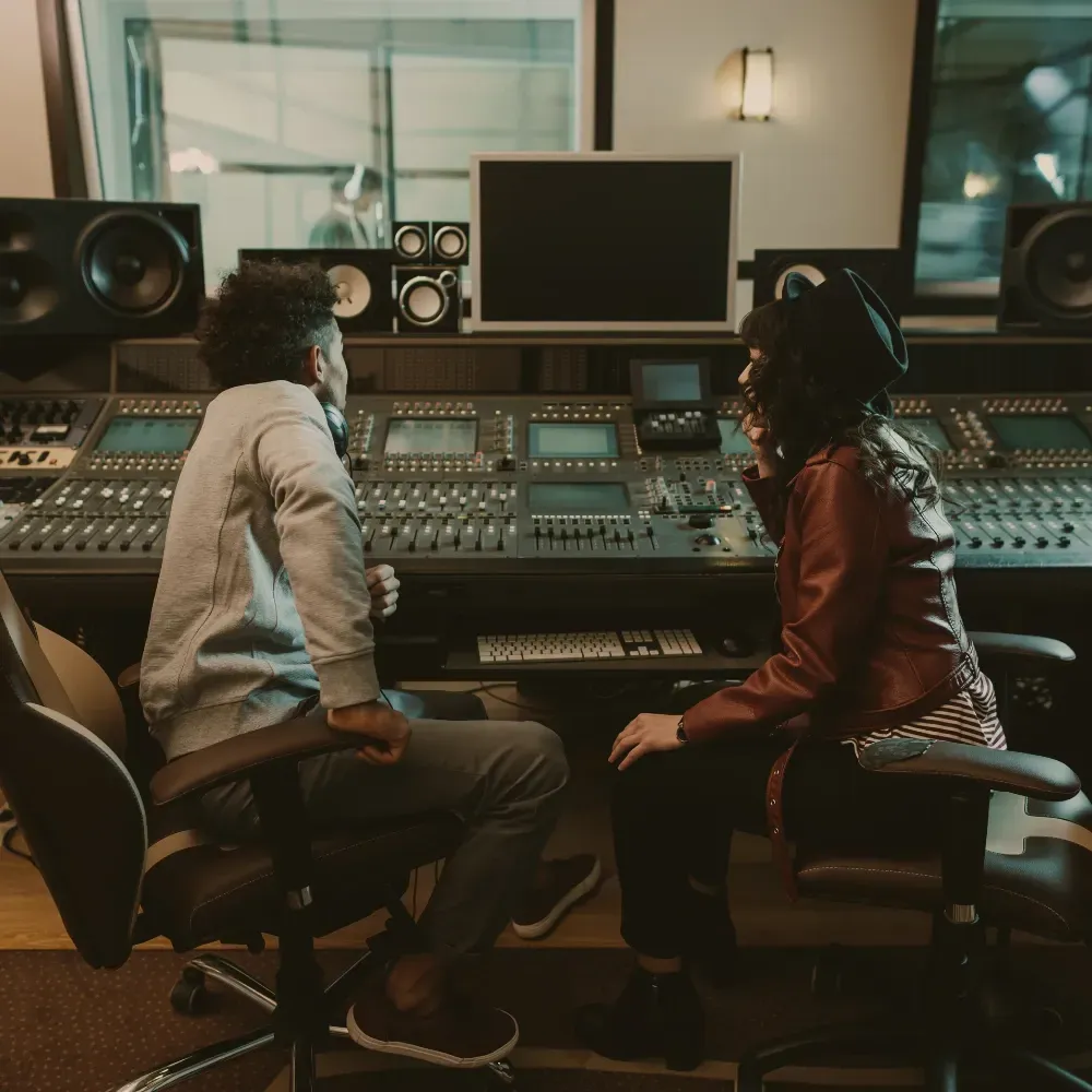 Two people adjusting levels at the base of an analog mixer, symbolizing strategic Google Ads management