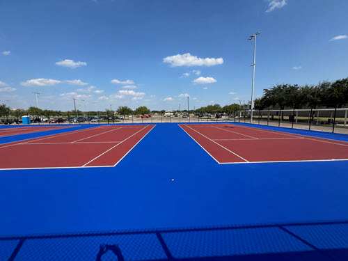 Tennis court construction site with base layers being prepared for surfacing