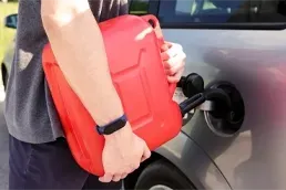 Emergency Fuel Delivery Service for Empty Tank Driver refueling car with gasoline can during emergency roadside fuel delivery service