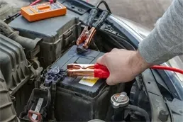 Car Battery Jump Start Service for Dead Battery Person using jumper cables to jump start a car battery during roadside assistance service