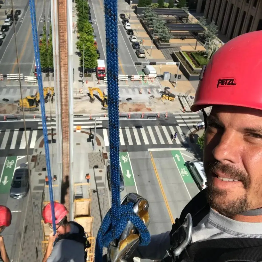 High-rise window cleaning specialist with safety harness cleaning downtown Oklahoma City building windows