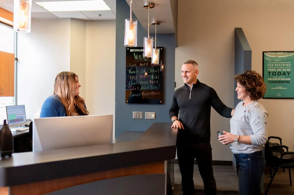 Total Spine Maple Grove chiropractic clinic reception with provider and visitor