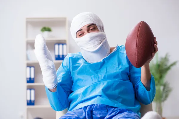 Athletic trainer and parent with high school football player on bench