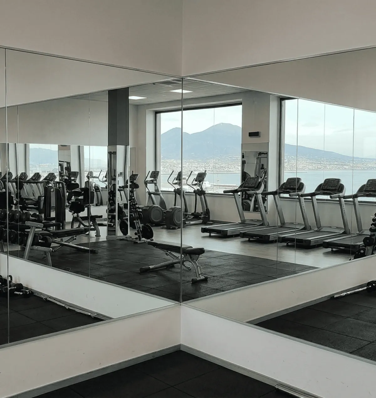 Floor-to-ceiling gym mirrors reflecting a modern, well-lit workout area in Naples