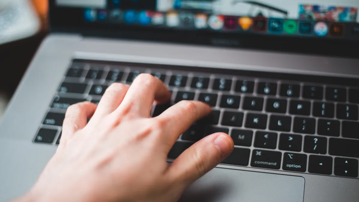 Open computer with a hand typing on the keyboard