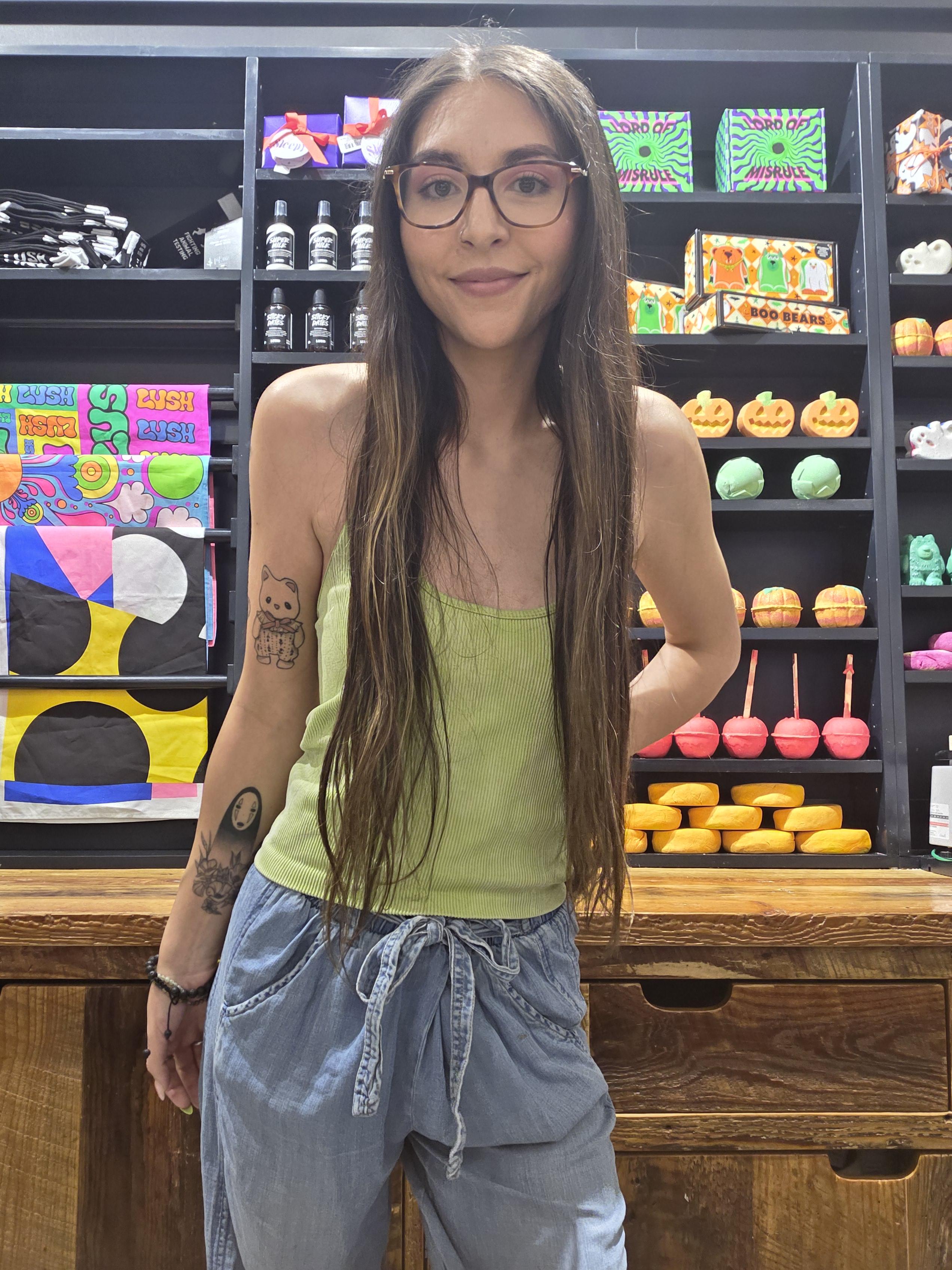 Katalina standing in front of Lush display wall behind the counter.
