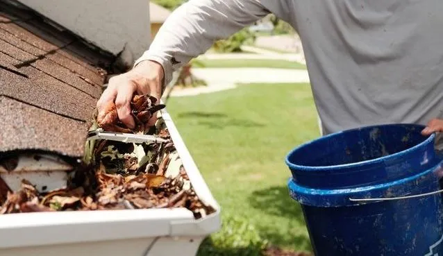 Image of man cleaning gutters by hand