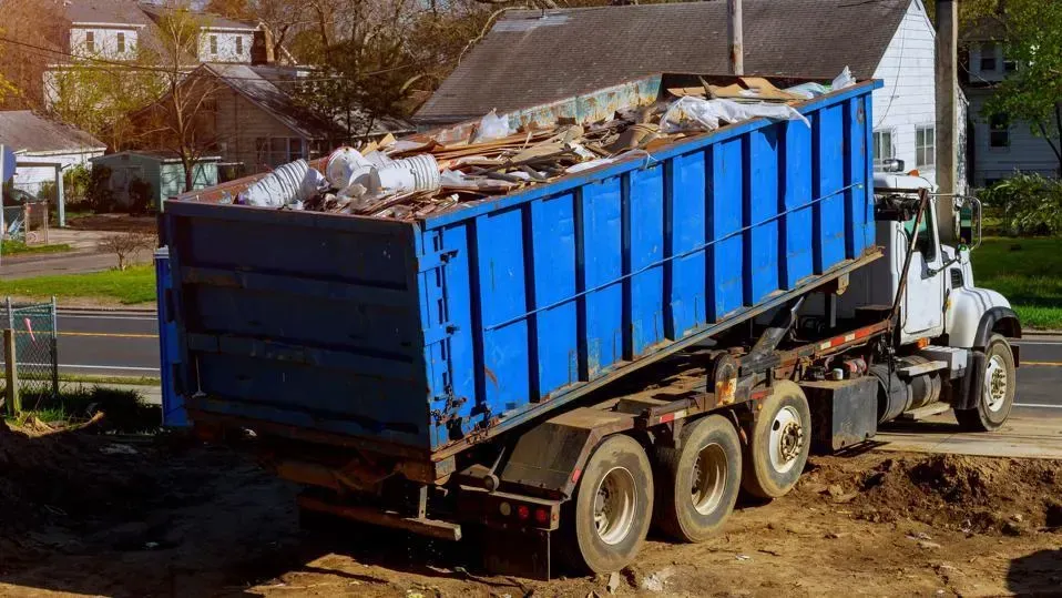 blue truck container containing wooden items and a lot of construction junk