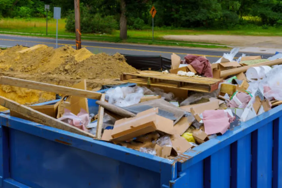 construction dirt, wooden planks, rubbish and cardboard loaded in large blue containers