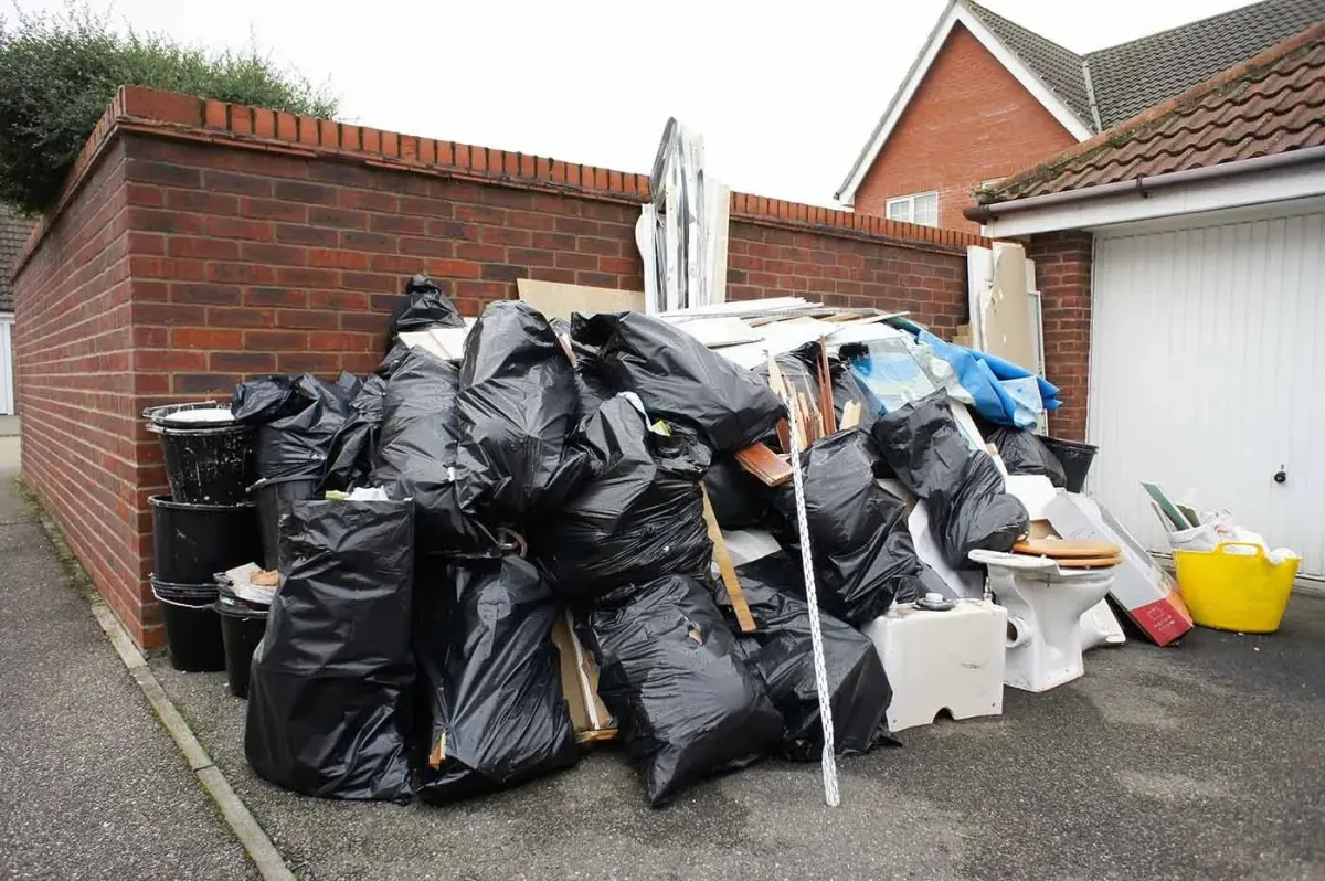 trash bags accumulating next to brick wall