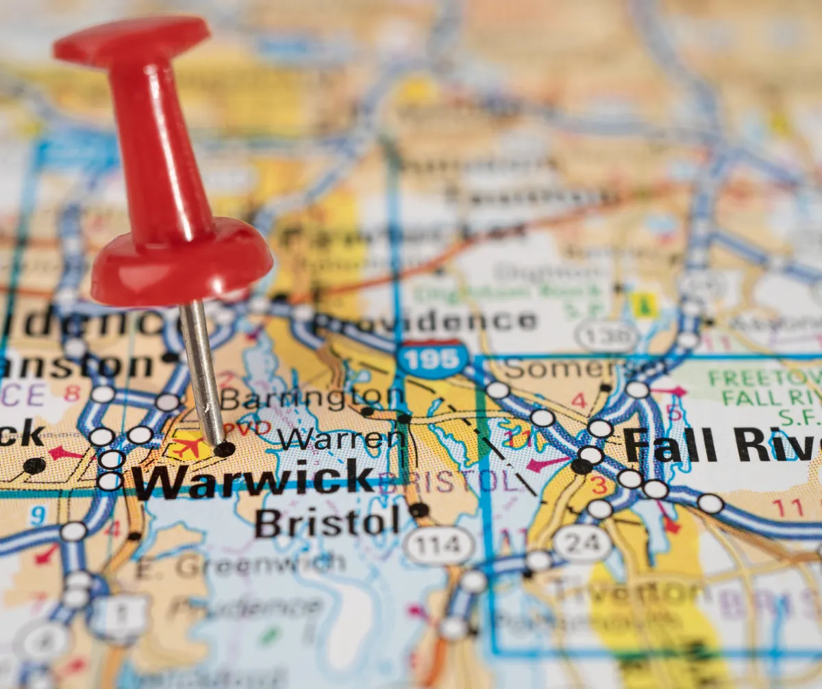 Close-up of a Rhode Island map with a red pushpin marking Warwick, highlighting statewide coverage for local small business AI services.
