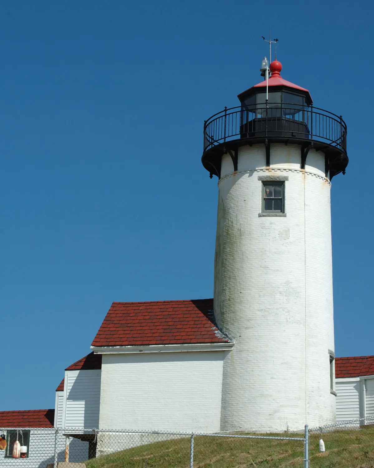 "White lighthouse with red roof under clear sky, symbolizing guidance and reliability for Rhode Island AI’s local businesses."