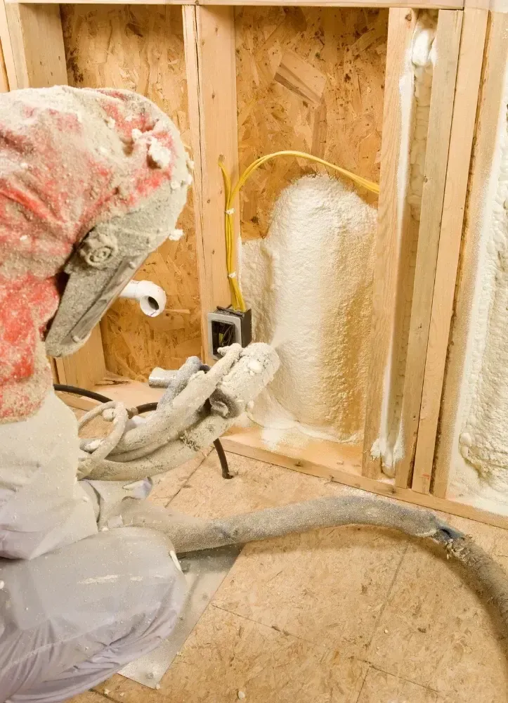Certified technician applying closed-cell spray foam in wall cavity in Panama City FL by Blue Line Insulation