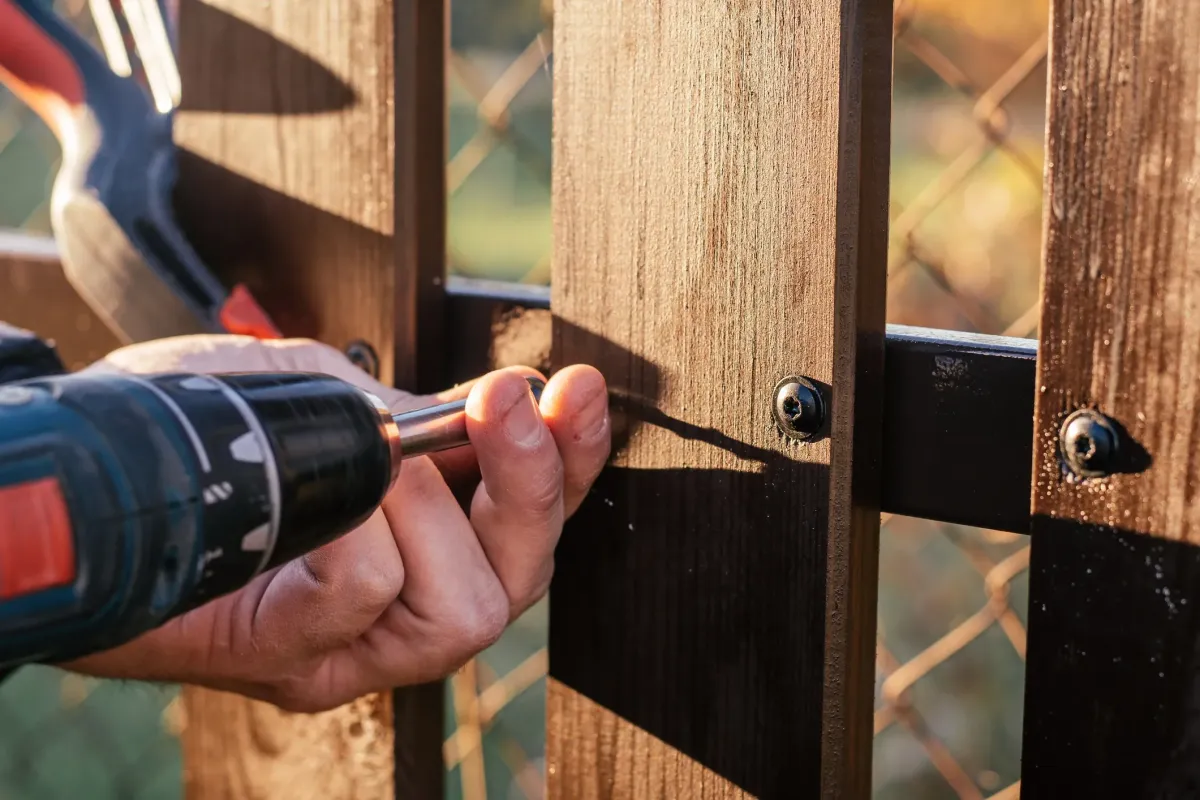 wWoden fence being assembled with an electric drill and screw during residential fencing installation