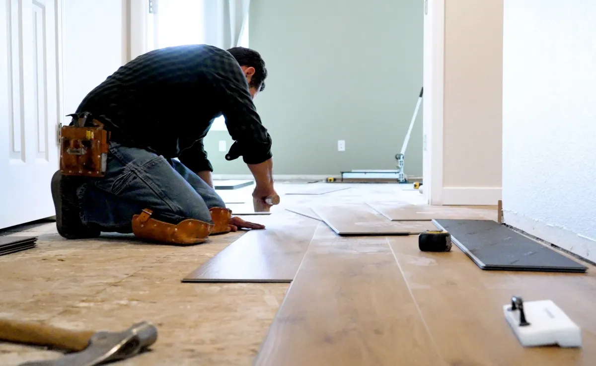 Person installing wooden flooring in a residential interior, showcasing construction skills relevant to Parker Built Construction LLC's remodeling services.