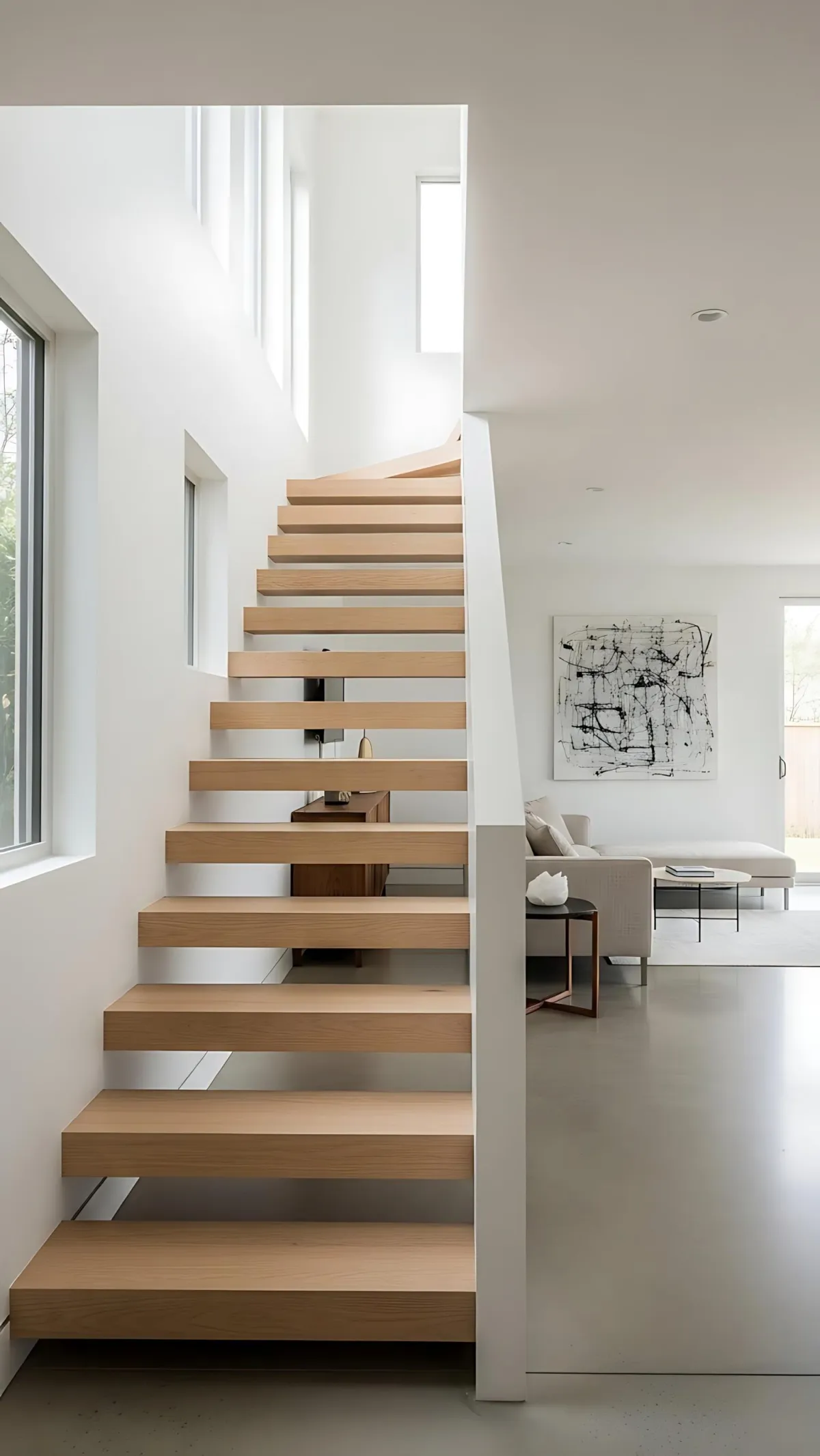 Modern open staircase with floating wooden steps in a bright, minimalist home interior with natural light.
