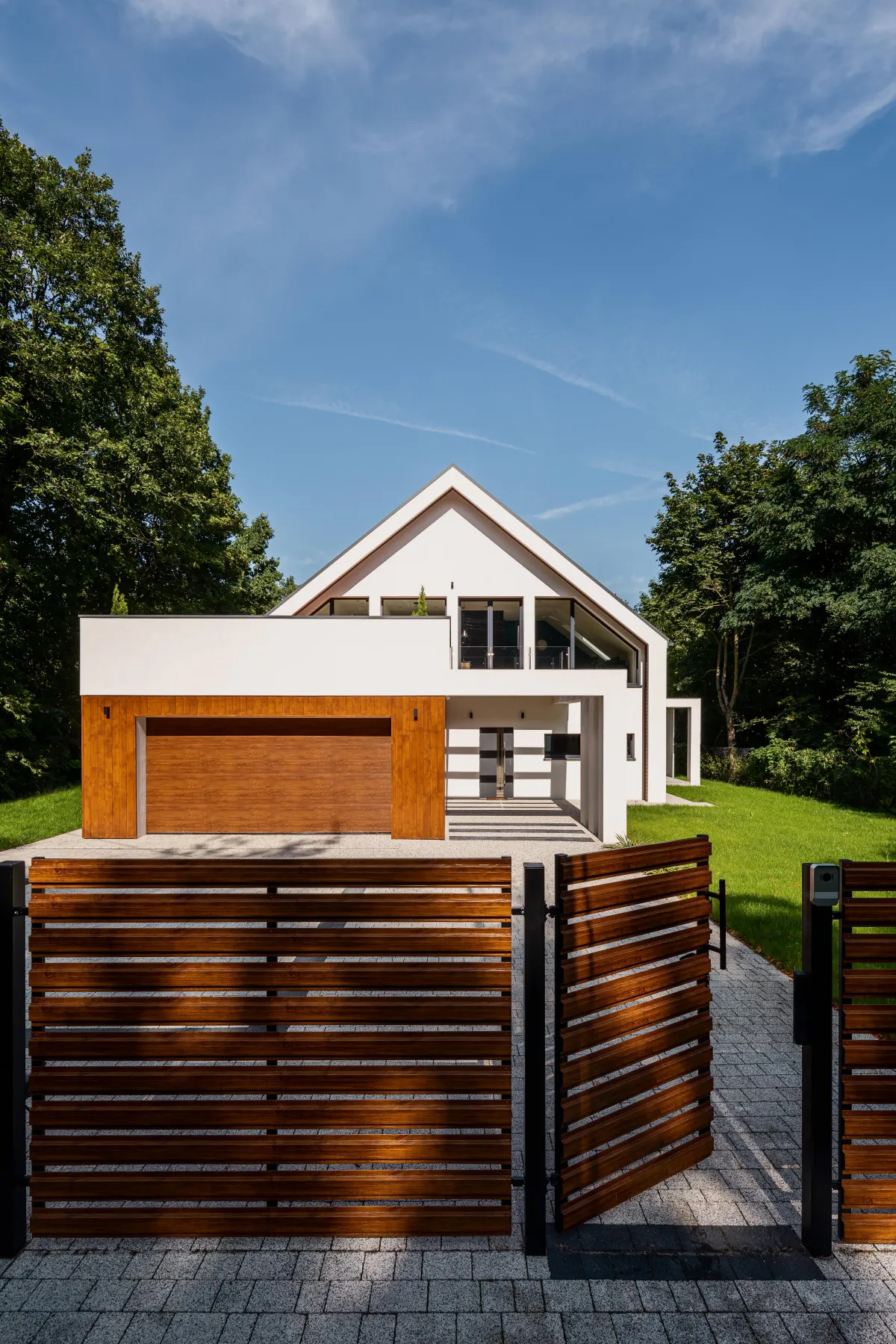 Modern residential home with a wooden slat gate and fence, featuring a contemporary exterior design and landscaped greenery.