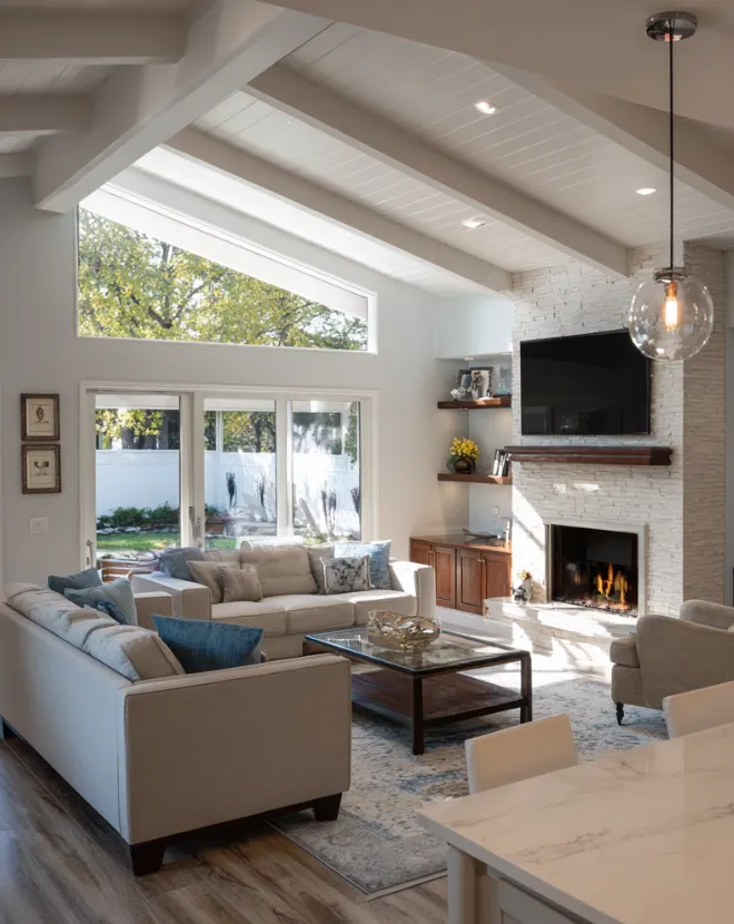 Modern Florida living room renovation with vaulted ceiling, fireplace, and natural light designed by Dream Design Building Group