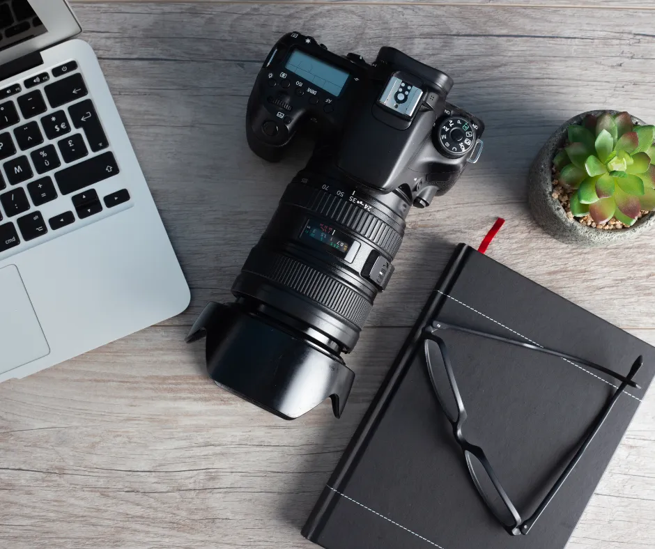 Professional camera on a desk beside a laptop and notebook representing content creation, photography, and media production services