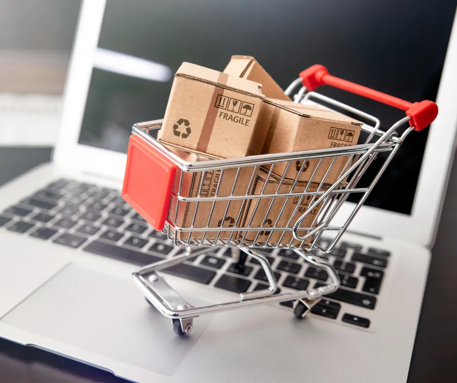 Mini shopping cart with packages on a laptop keyboard symbolizing e-commerce and Shopify store setup services.