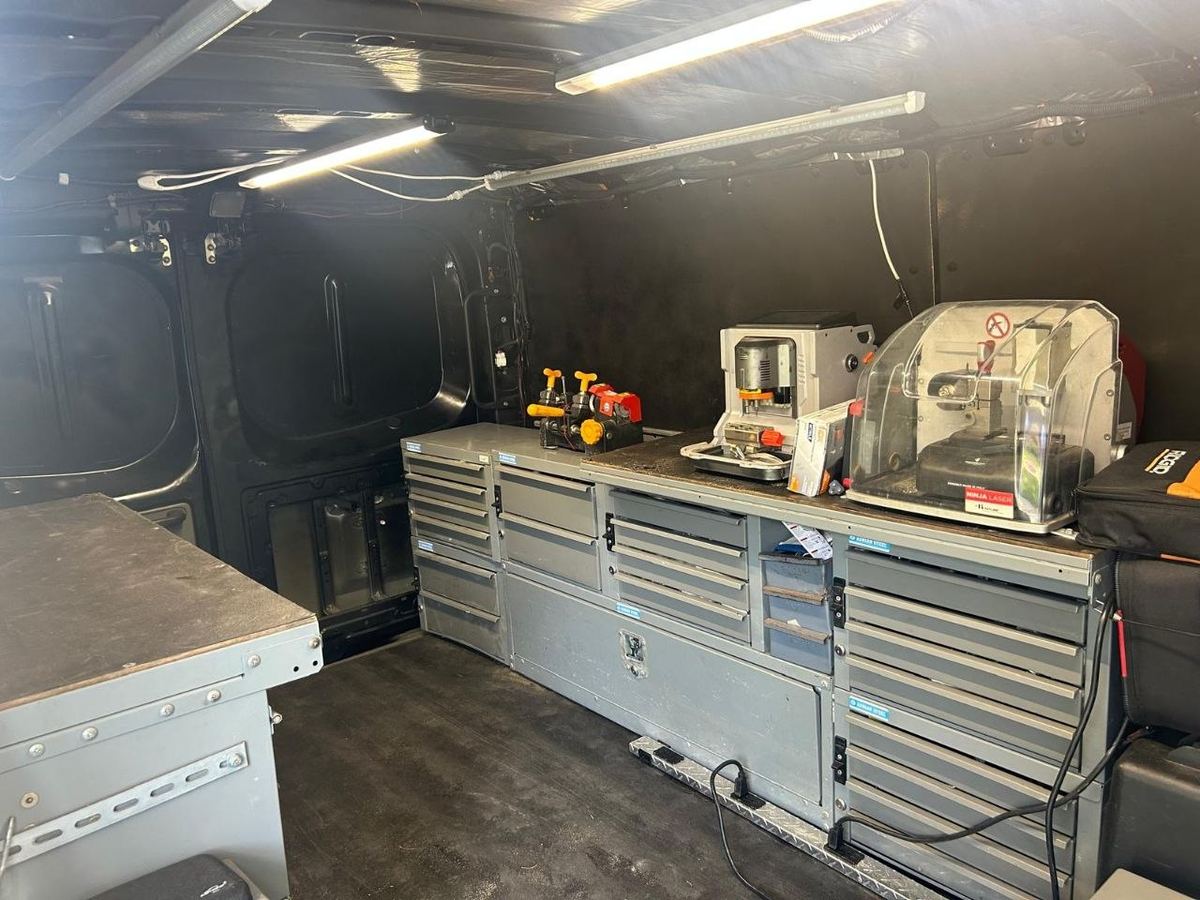 Key duplicators and a laser key-cutting machine on the van's workbench