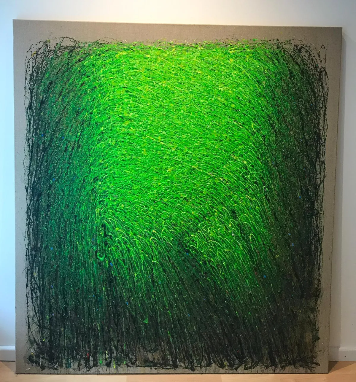 Grüne Wiese’ von Sadik Uslu: leuchtendes grünes Farbfeld mit gestischen, halmartigen Strichlagen und dunklem Rand; Acryl/Öl auf naturbelassener Leinwand.