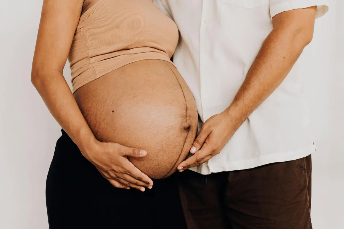 An expectant mother and her partner, hands resting on her bump