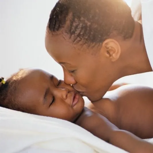 A mother kissing her sleeping baby on the cheek