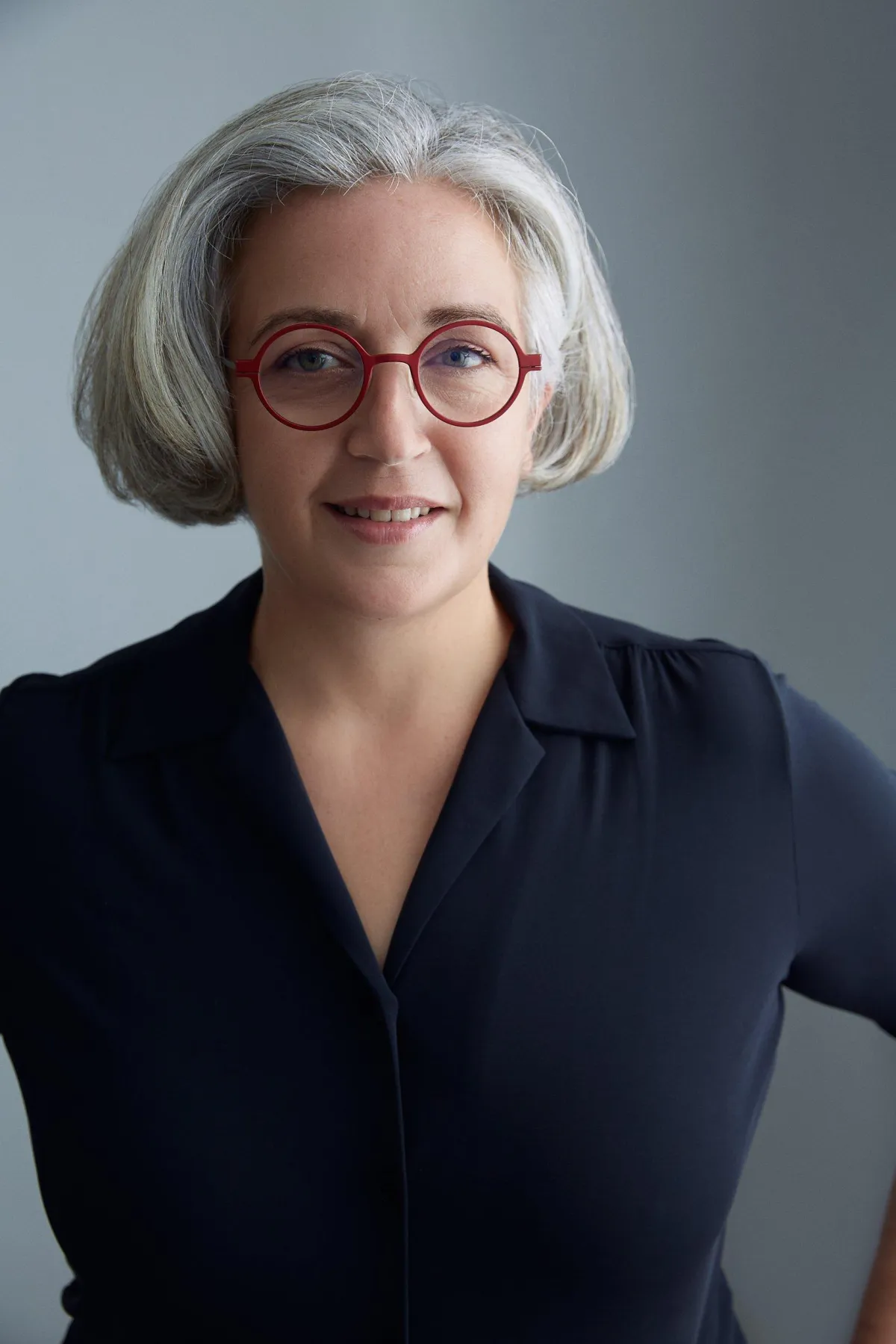Portrait of coach Josianne Robb, with the red round glasses that inspired her logo
