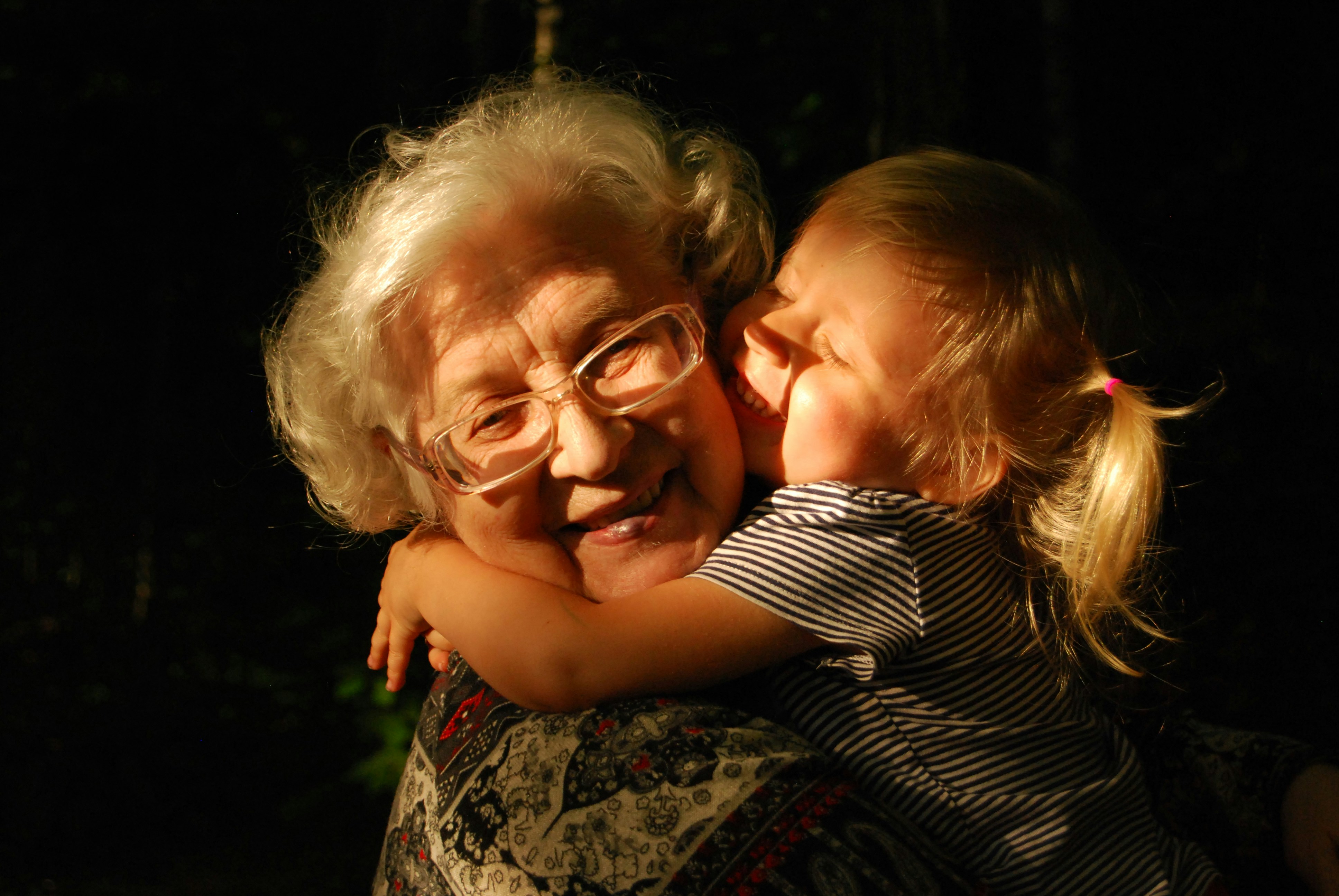 Smiling grandma getting hugs by young granddauhter