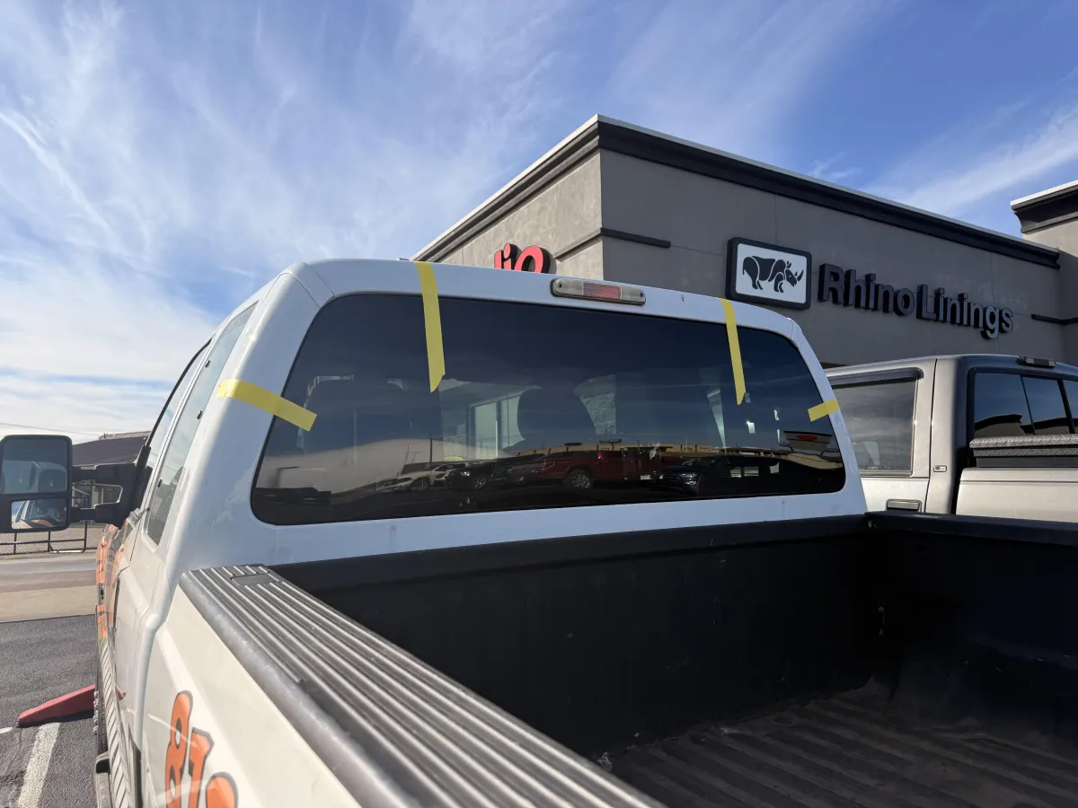 Technician applying car window tint film with squeegee
