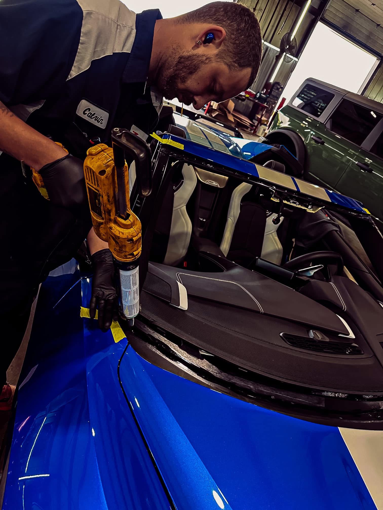 Technician applying car window tint film with squeegee