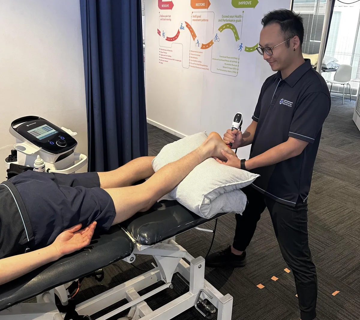 Physio treating client with shock wave therapy