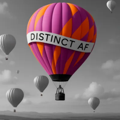 A vibrant pink and orange hot air balloon labeled ‘Distinct AF’ rising above black-and-white balloons, symbolizing Tanya Spencer’s group course on optimal distinctiveness, confidence, and visibility.