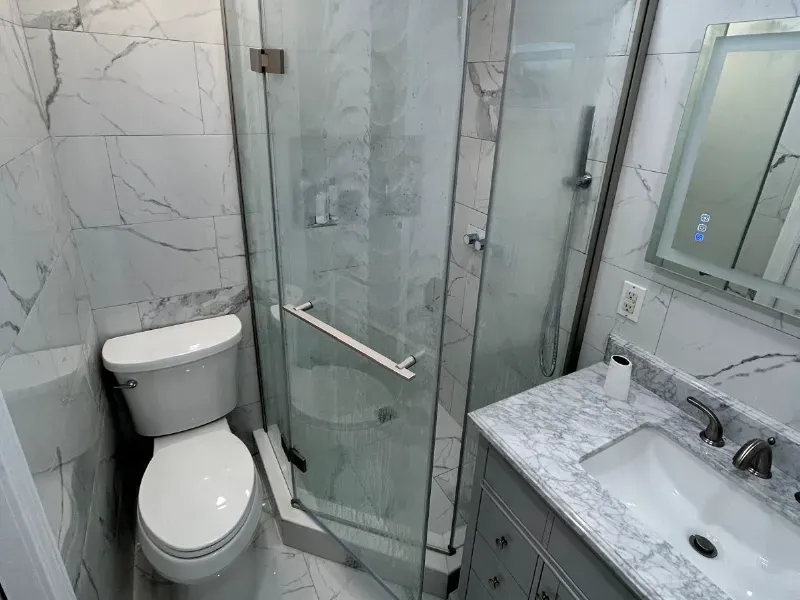 Small bathroom remodel with full Calacatta marble tile walls and floor, corner frameless glass shower enclosure and LED mirror by CLA New England Tile – Boston MA