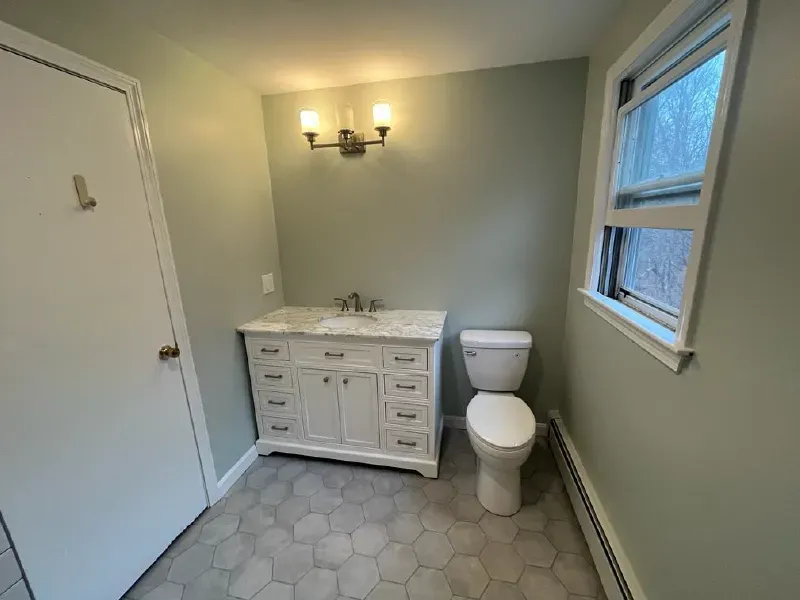 Clean bathroom remodel with gray hexagon porcelain floor tile, white shaker vanity, and marble countertop by CLA New England Tile – Greater Boston Area