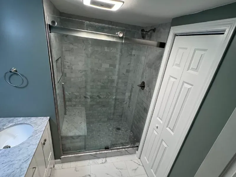 Bathroom remodel with marble subway tile walk-in shower, sliding frameless glass door, mosaic tile floor and Calacatta porcelain floor tile by CLA New England Tile – Boston MA