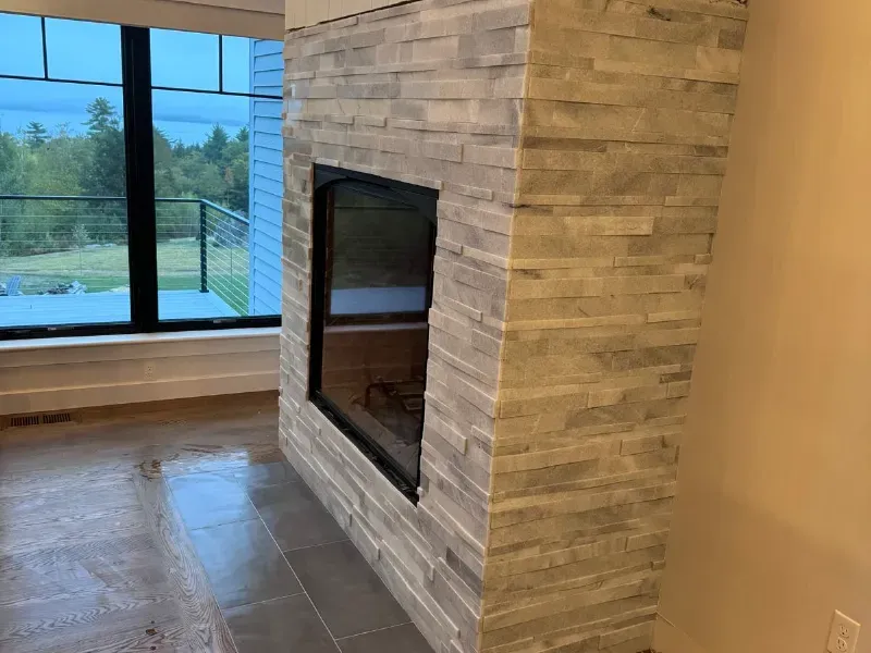 Custom stacked ledger stone tile fireplace surround with porcelain hearth floor in new construction home by CLA New England Tile – Massachusetts