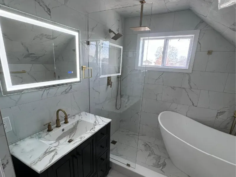 Luxury marble tile bathroom remodel with freestanding tub, frameless glass shower, and gold fixtures by CLA New England Tile – Boston MA