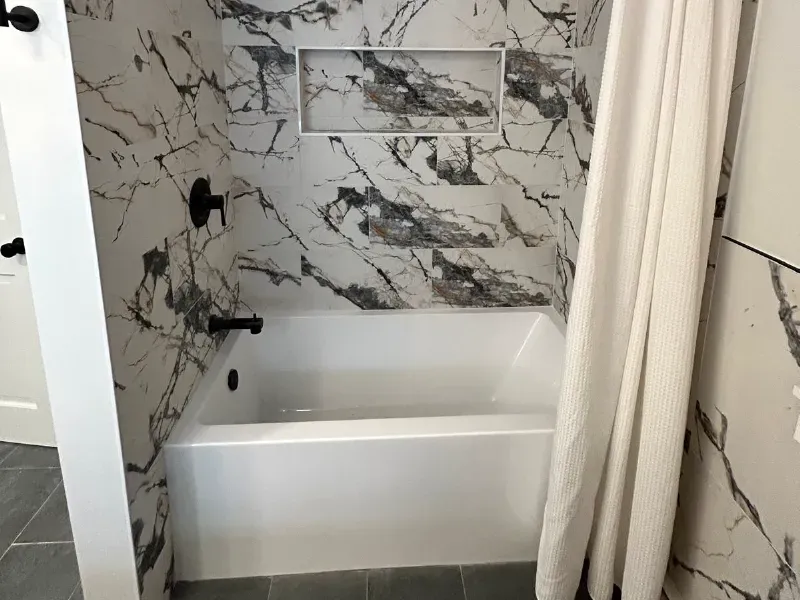 Double vanity bathroom with large-format marble tile backsplash, LED backlit mirror, and gold faucets installed by CLA New England Tile – Greater Boston Area