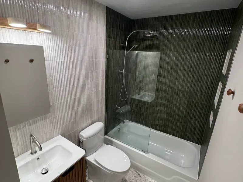 Modern bathroom remodel featuring fluted ribbed wall tile in sage green, terrazzo floor, and bamboo-style vanity installed by CLA New England Tile – Massachusetts
