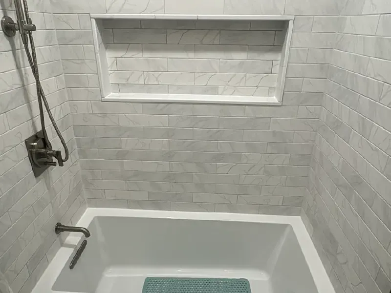 Professional tile installation featuring marble subway tile tub surround, recessed niche, and hexagon floor tile by CLA New England Tile – Greater Boston MA
