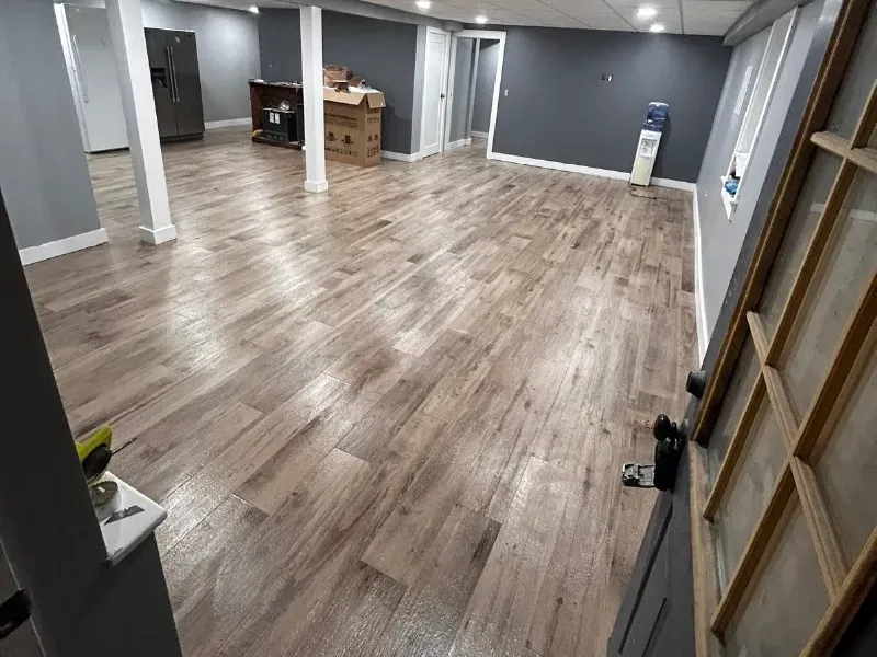 Basement renovation with demolition, subfloor preparation, and large-format wood-look porcelain tile installation by CLA New England Tile – Greater Boston Area