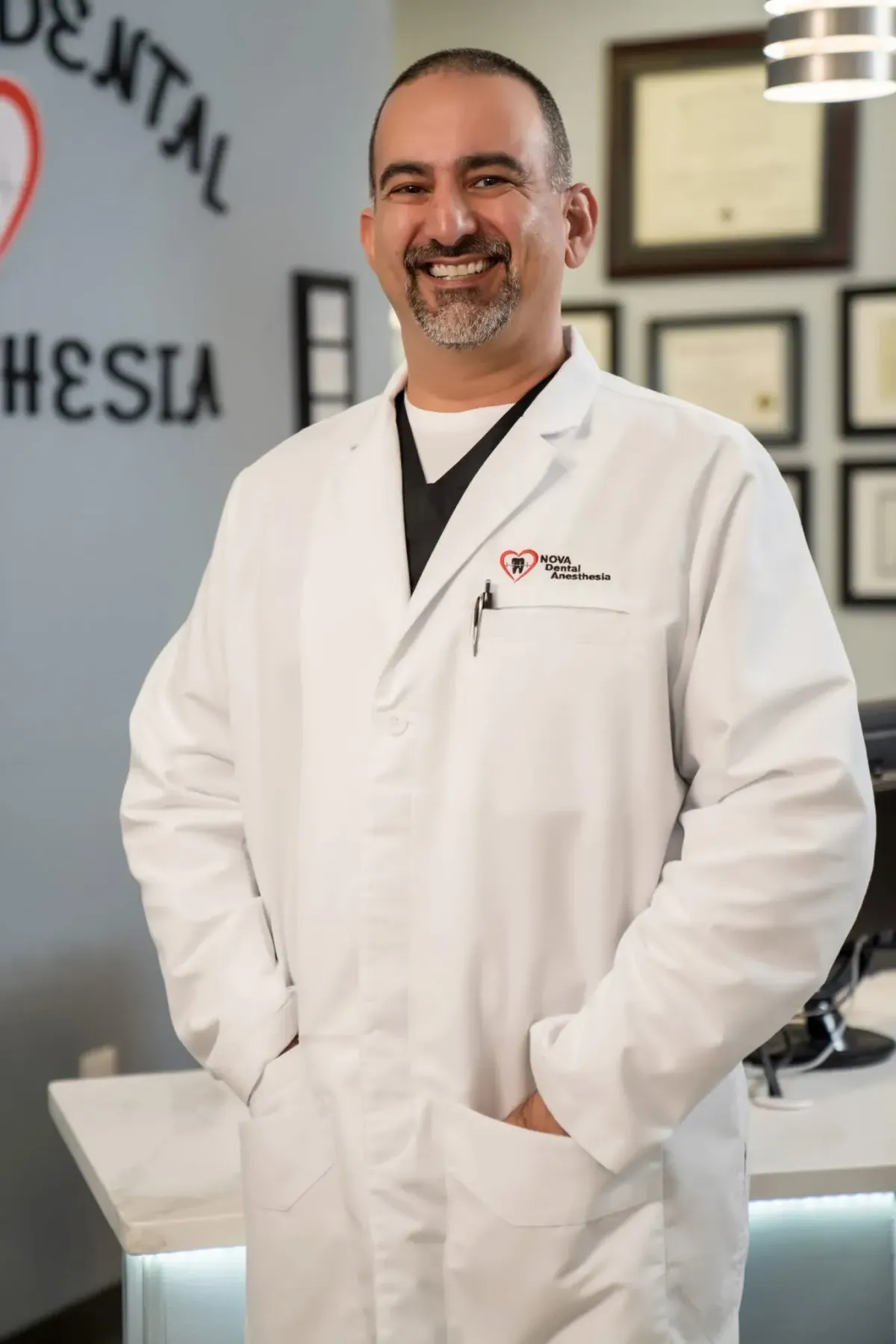 Full-body portrait of a female anesthesiologist in her 50s wearing a white coat, standing in a bright clinic hallway with soft depth of field, confident posture, warm natural lighting, professional and approachable, photorealistic, high-resolution, unobtrusive medical environment.