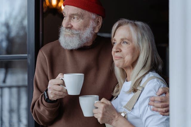 A hopeful young woman at a kitchen table, laptop open, smiling as she signs up for a spiritual course, with morning sunlight streaming through a window and a mug beside her.
