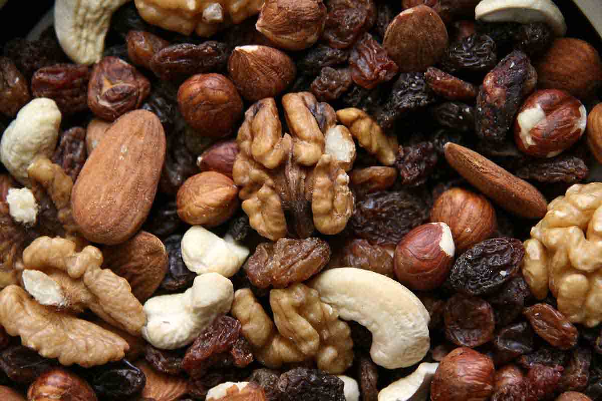 A top-down view of a rich assortment of raw nuts and dried fruits, illustrating nutritional factors and potential dietary triggers in a holistic allergy analysis.