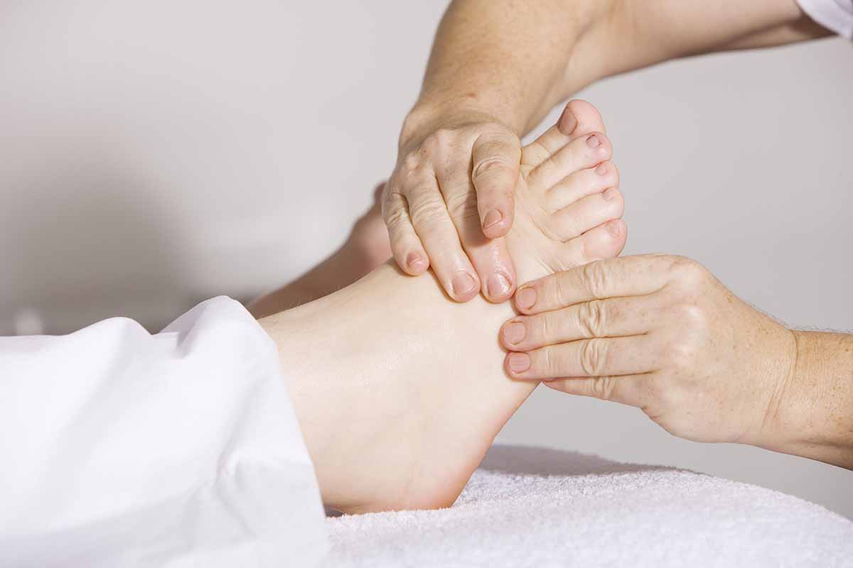 A close-up shot of a massage therapist's hands applying targeted pressure to a patient's foot during a relaxing therapeutic massage session.